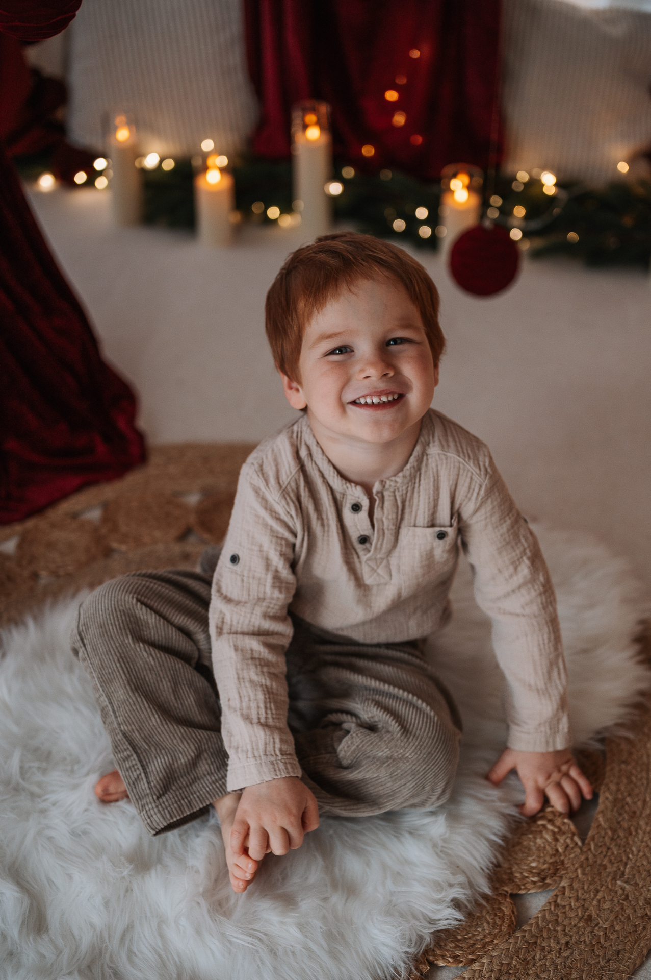 Kind lacht im Weihnachtsset bei den Weihnachtsminis von Leuchtraum Fotografie, Familienfotografie Starnberg und München